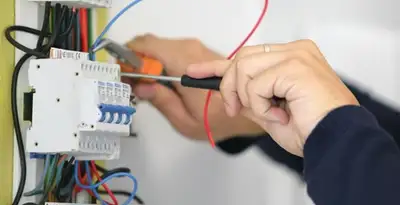 Electrician installing and adjusting circuit breakers in an electrical panel in Madison, WI